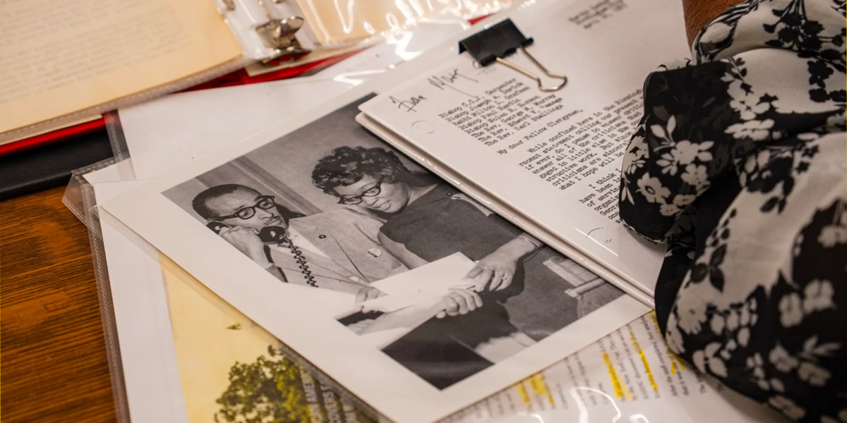 An overhead view of archival documents on a wooden table, including a black-and-white photo of Rev. Wyatt Tee Walker and Willie Pearl Mackey next to an early typed draft of Martin Luther King Jr.’s "Letter from Birmingham Jail."